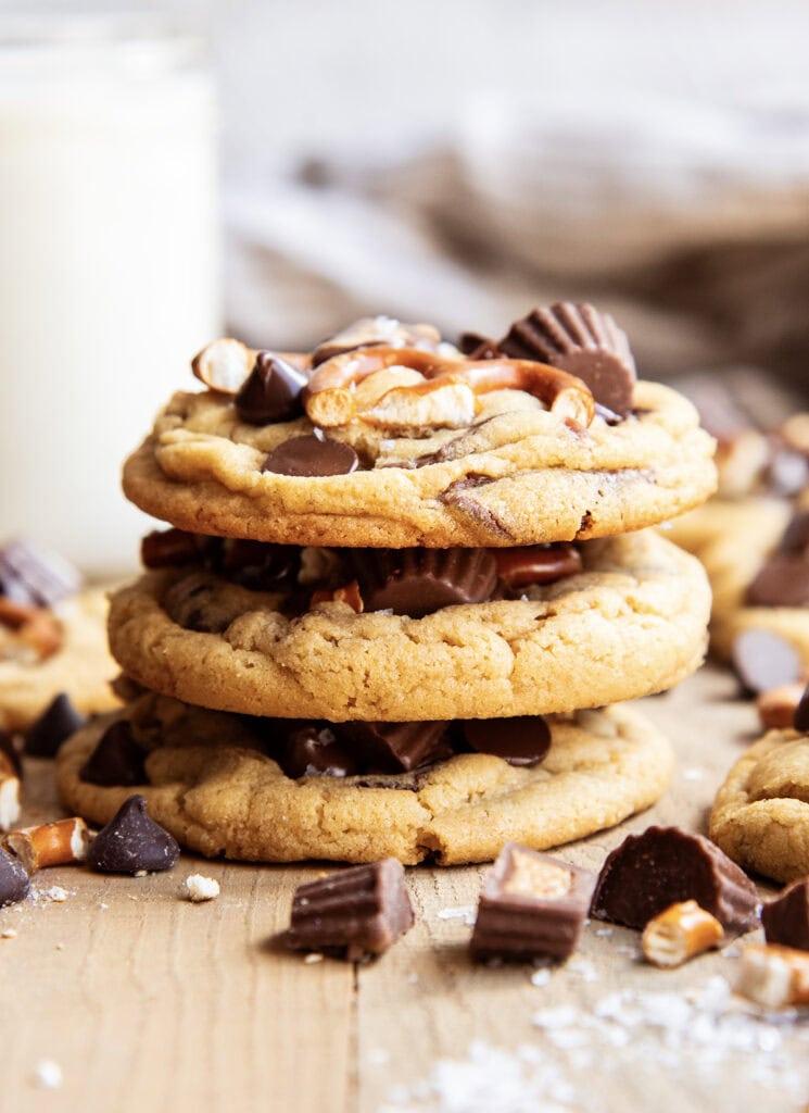 A stack of three peanut butter pretzel cookies topped with mini pretzels, and peanut butter cups.
