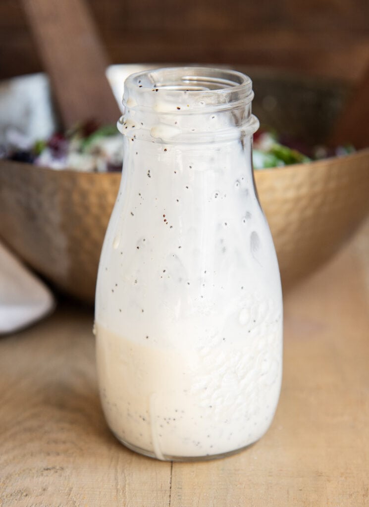 A bottle of poppy seed dressing, with the dressing up the side of the bottle from being poured out.