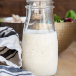 A bottle of poppy seed dressing next to a white and black striped towel.