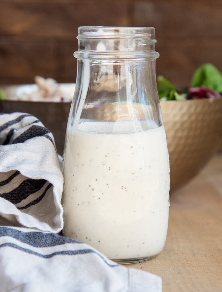 A bottle of poppy seed dressing next to a white and black striped towel.