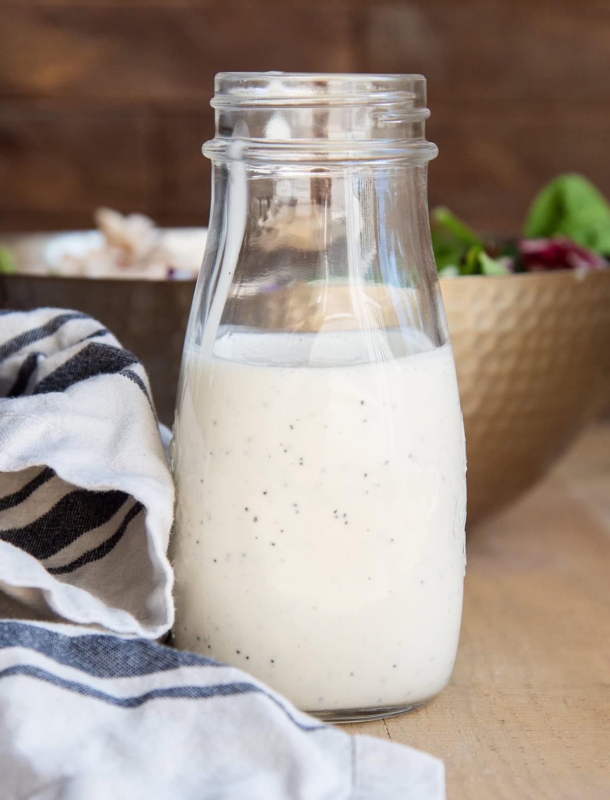 A bottle of poppy seed dressing next to a white and black striped towel.