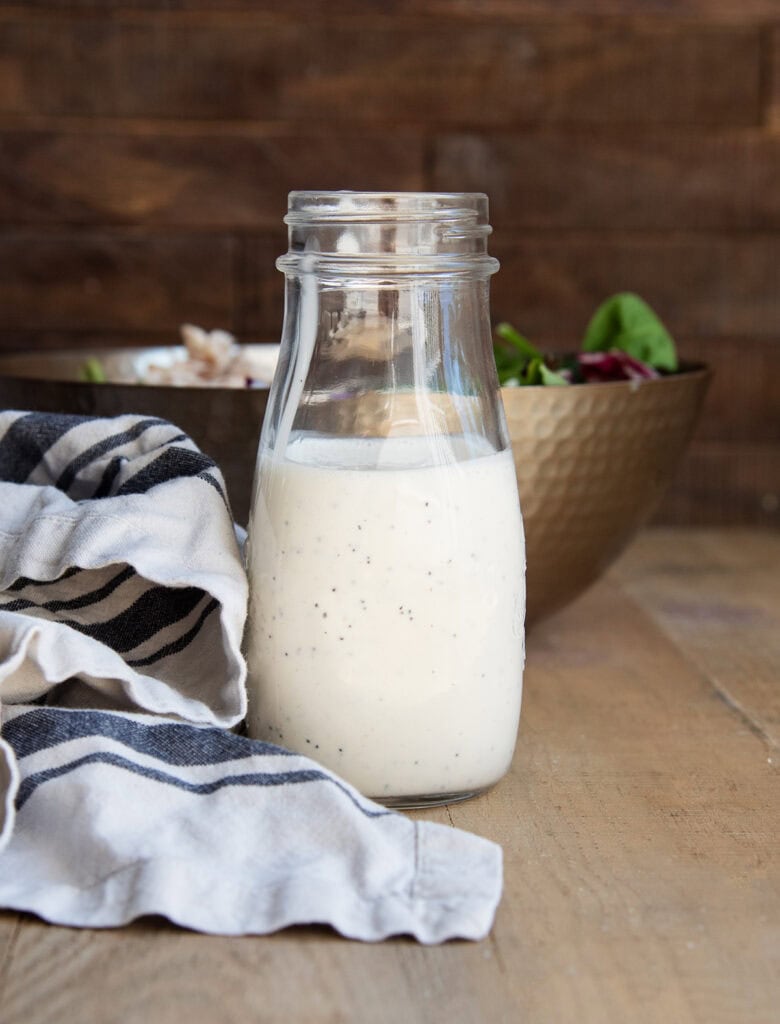 A bottle of poppy seed dressing next to a white and black striped towel.