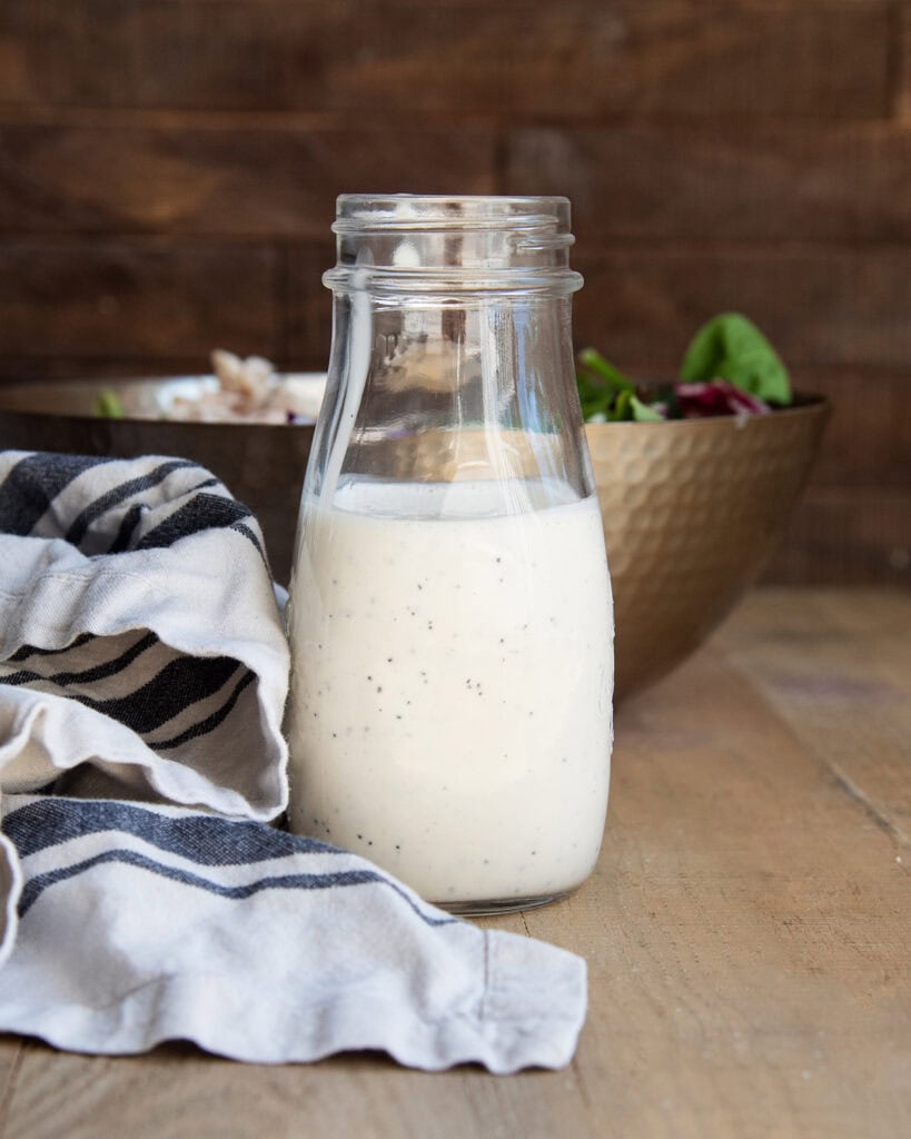 A bottle of poppy seed dressing next to a white and black striped towel.