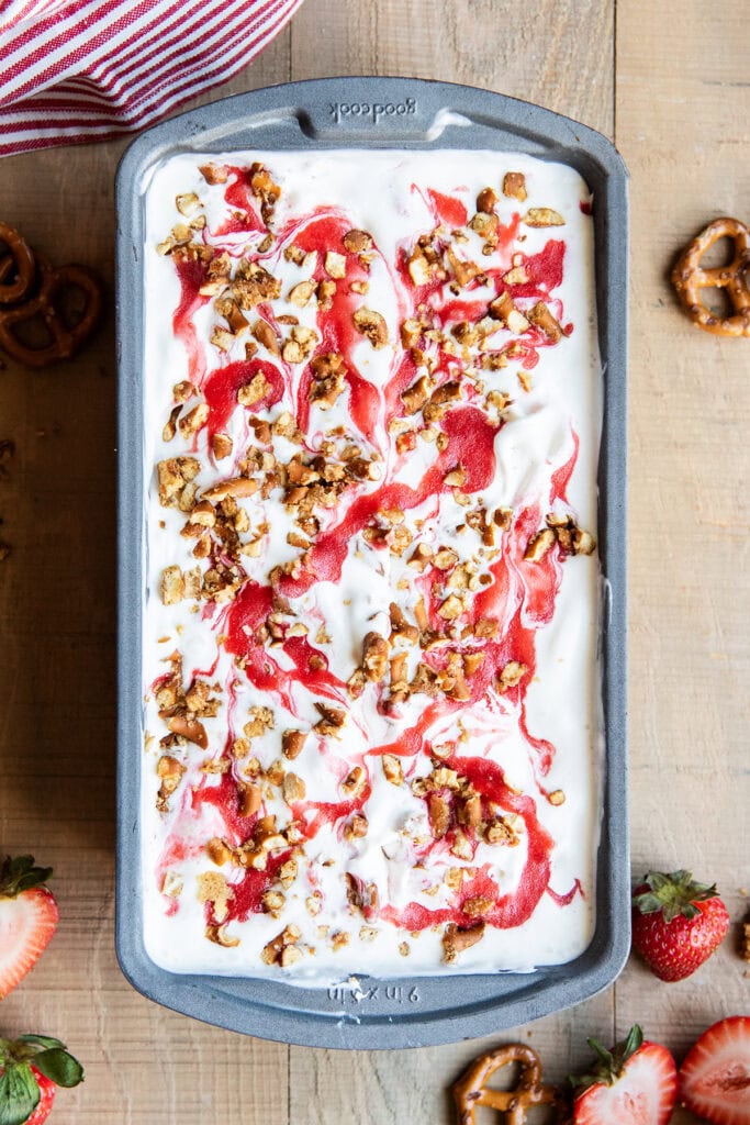 An above view of strawberry pretzel ice cream with a strawberry swirl, and pretzel crunch on top.