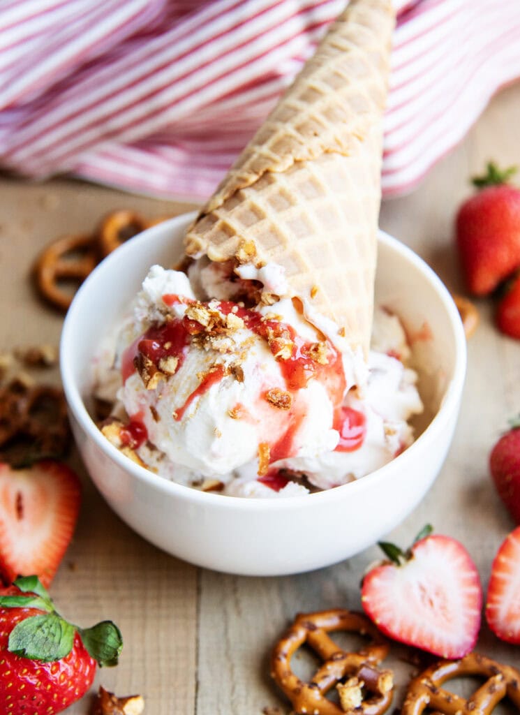 A bowl of strawberry pretzel salad ice cream with a cone on top.