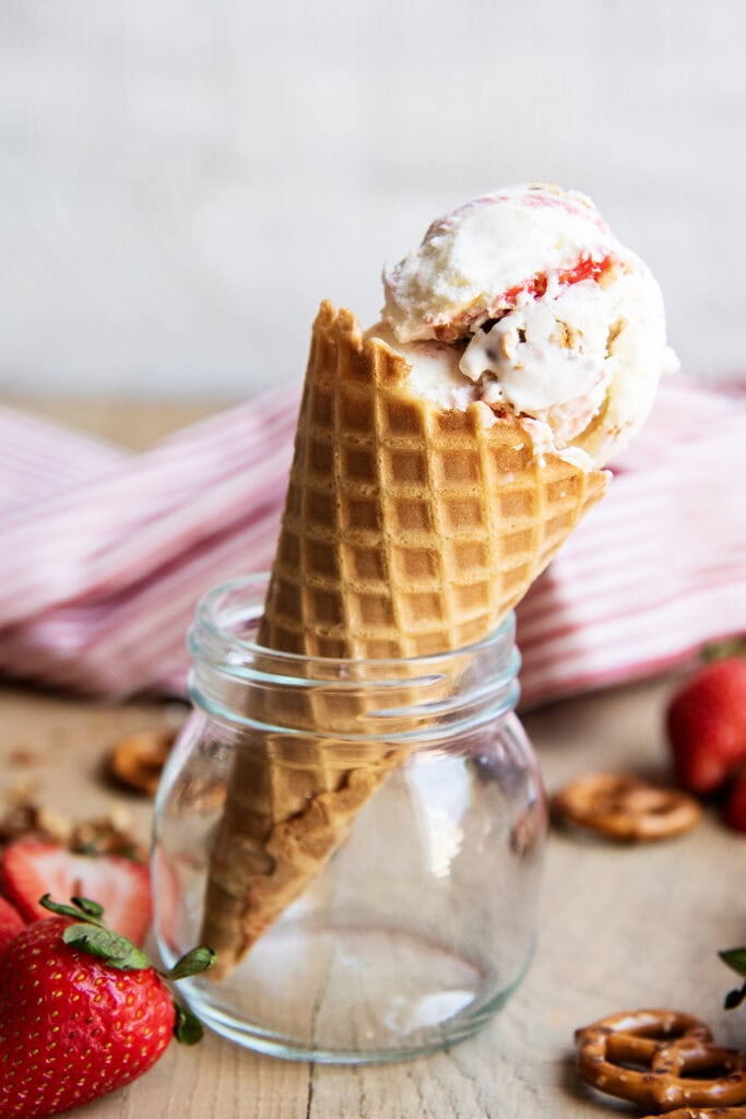 A cone of strawberry pretzel pie ice cream sitting in a jar.