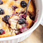 A pan of blackberry cobbler with a scoop of it on a spoon.