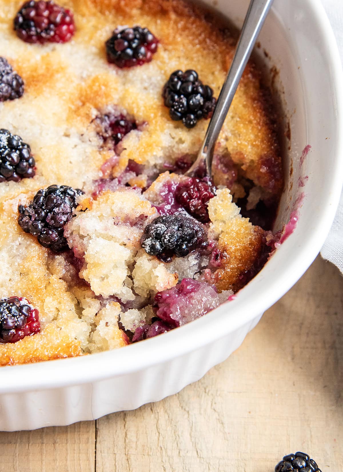 A pan of blackberry cobbler with a scoop of it on a spoon.