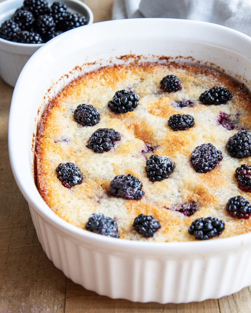 An above view of a baking dish full of blackberry cobbler and topped with blackberries.