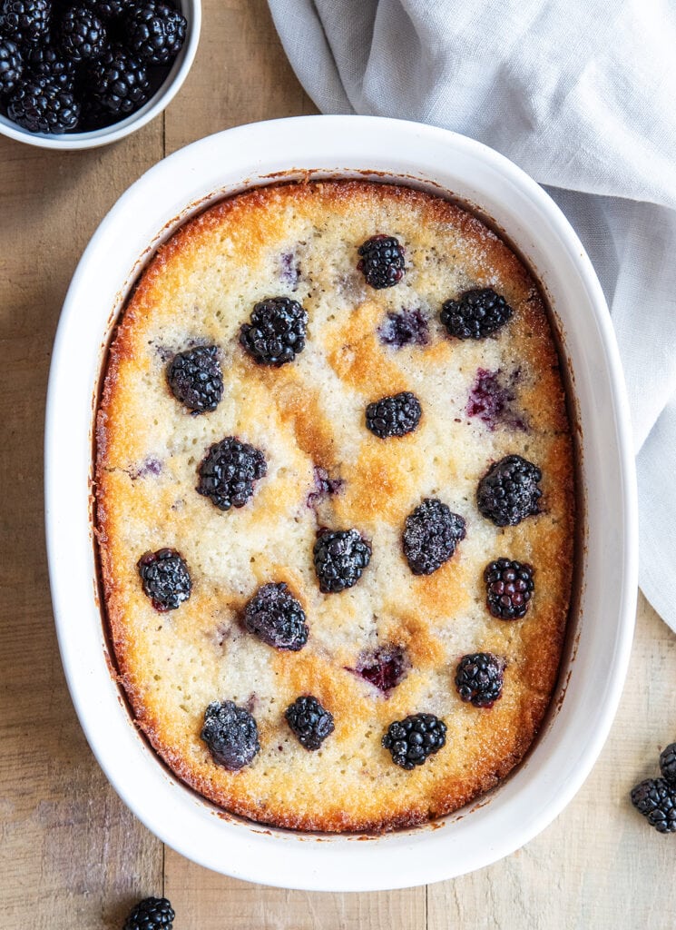 An above view of a baking dish full of blackberry cobbler and topped with blackberries.