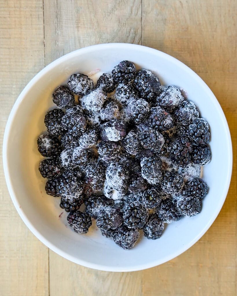 A bowl of blackberries topped with sugar.