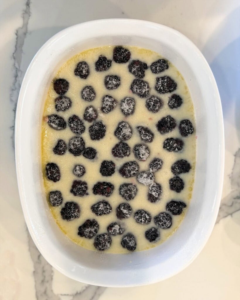 Blackberry cobbler batter unbaked topped with fresh blackberries.