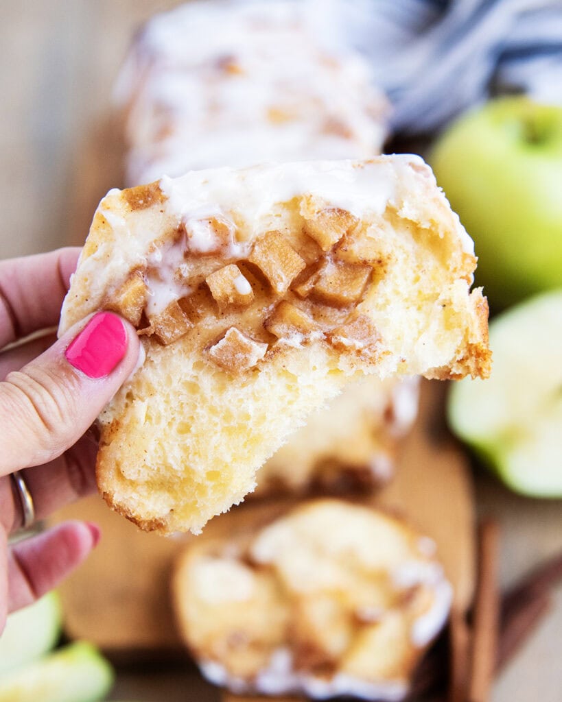 A hand holding a piece of apple pull apart bread.