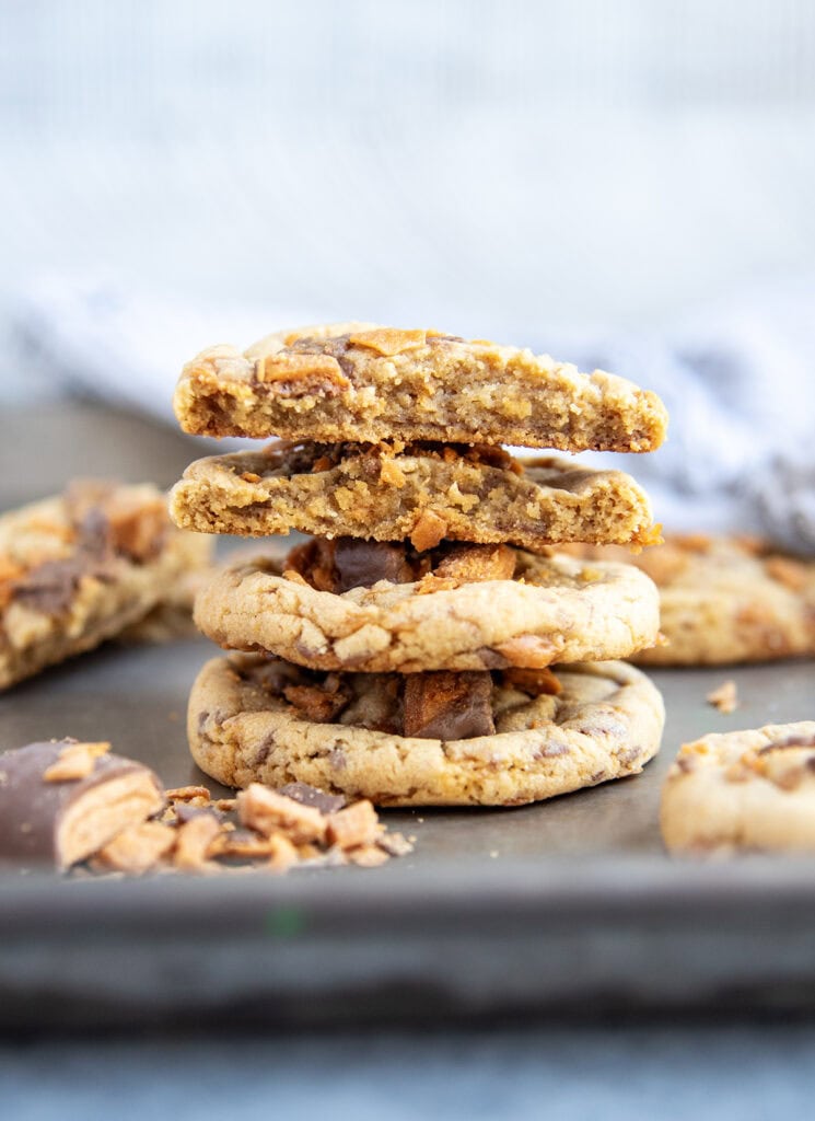 A stack of peanut butter butterfinger cookies, and the top two cookies are halves of cookies showing the middle of the cookies.