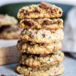 A stack of several chocolate chip zucchini cookies and the top cookies are broken in half showing the center of the cookies.