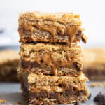 A stack of three oatmeal cookie butter cookie bars with gooey cookie butter coming out of the bars.