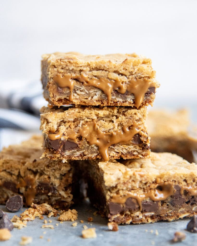 A stack of three oatmeal cookie butter cookie bars with gooey cookie butter coming out of the bars.